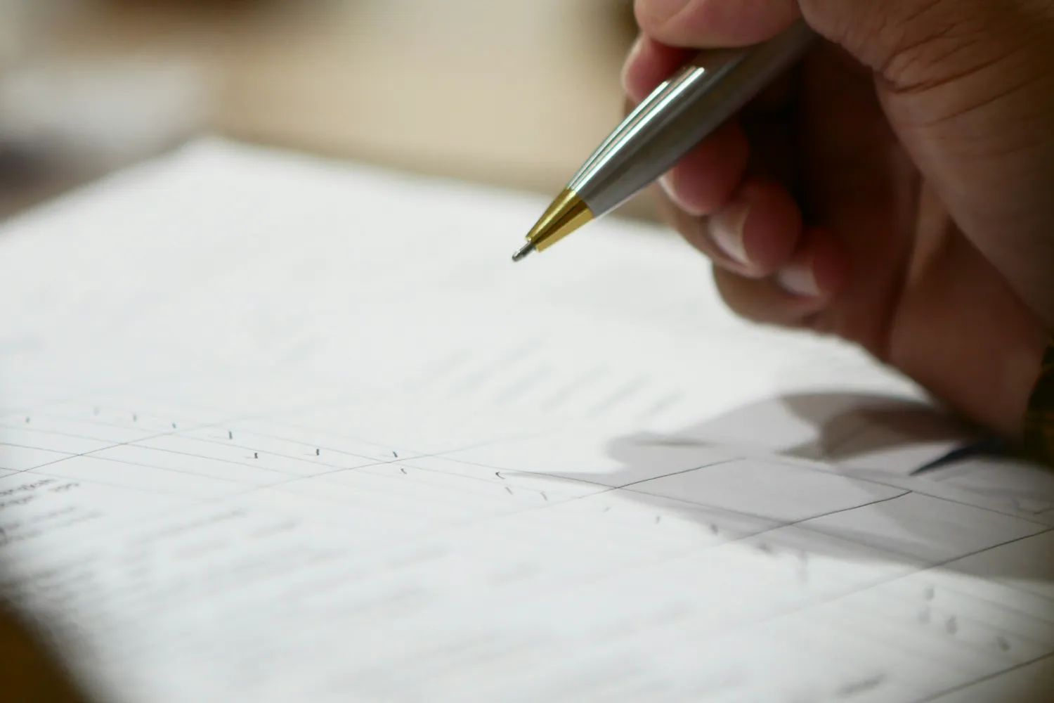 Main relisant un document imprimé, stylo en main