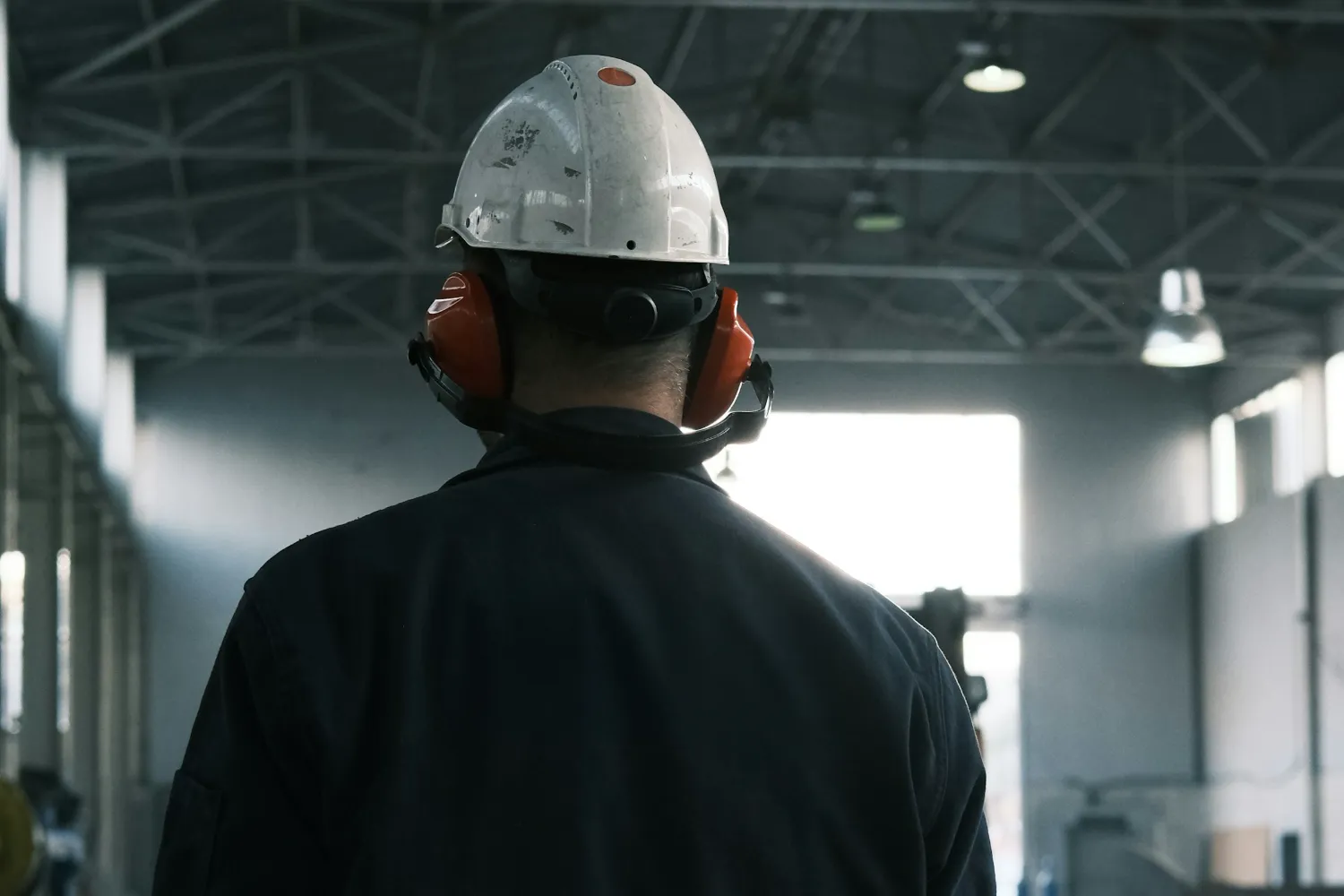 Ouvrier de dos, casque de sécurité, dans un atelier de production