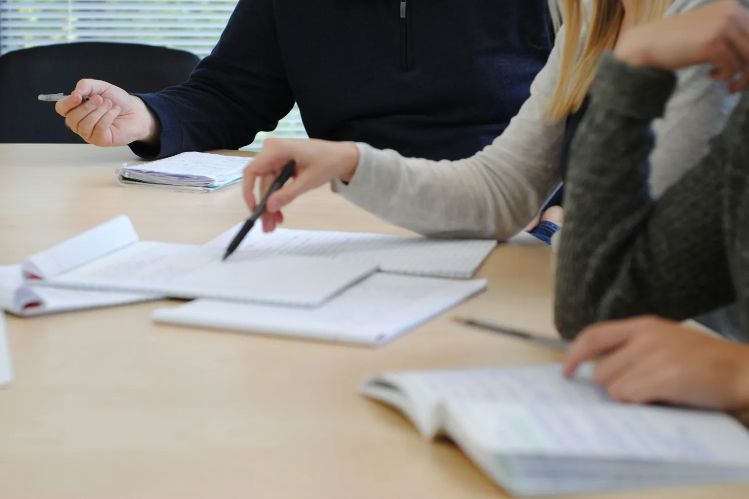 Séance de travail autour d’une table, documents et carnets ouverts