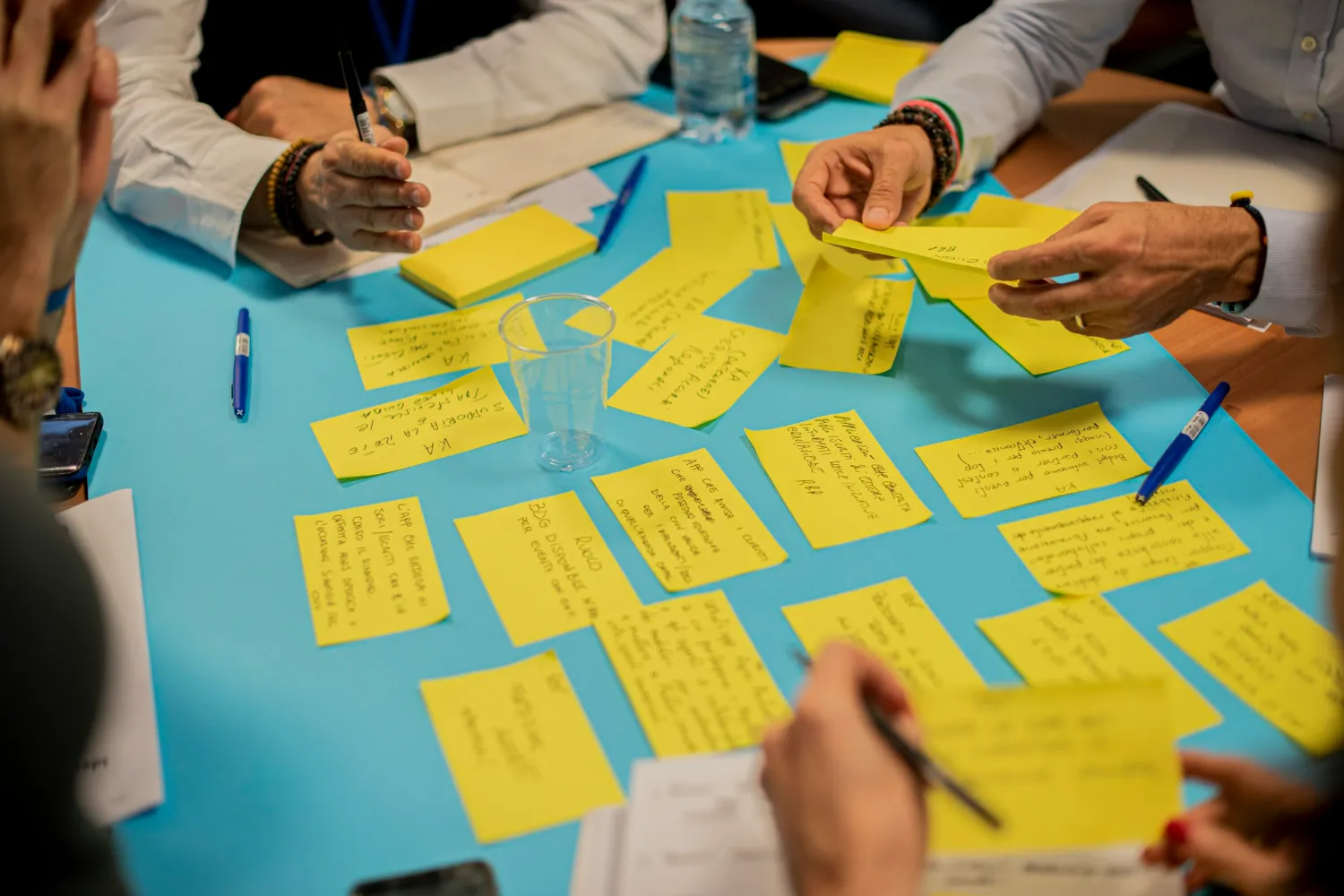 Mains autour d’une table d’atelier couverte de notes autocollantes